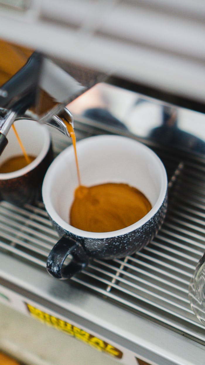 Close-up of fresh espresso shot pouring into a coffee cup from a modern machine.